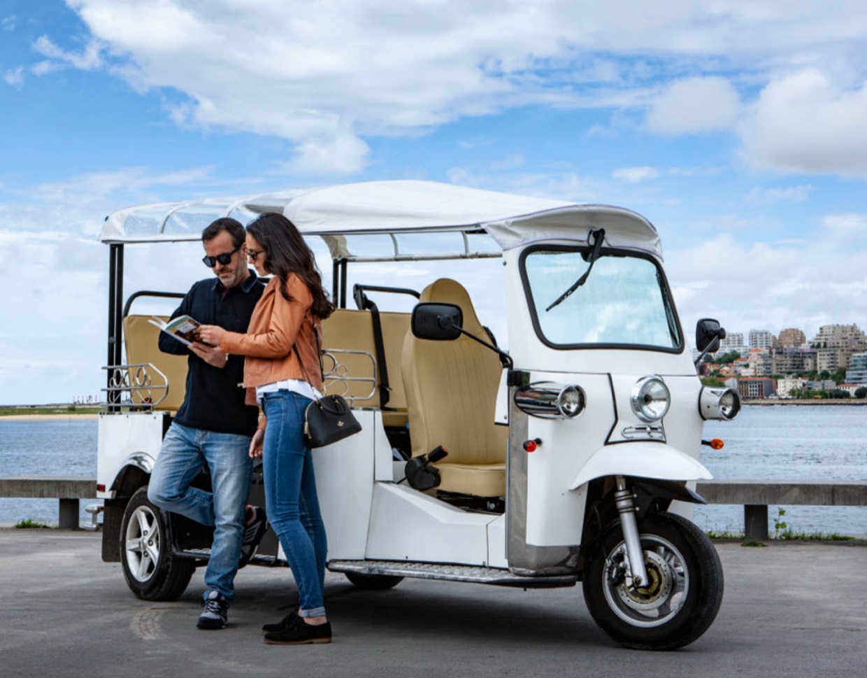 Weisses dreirädriges Personen-TukTuk von e-Tuk an einer Uferpromenade.