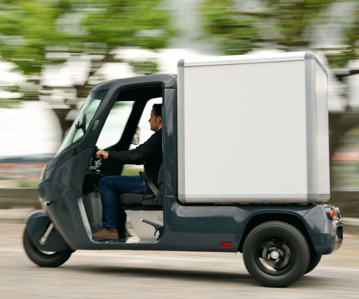 Graues dreirädriges Transport-TukTuk von e-Tuk mit Kofferaufbau in Fahrt.
